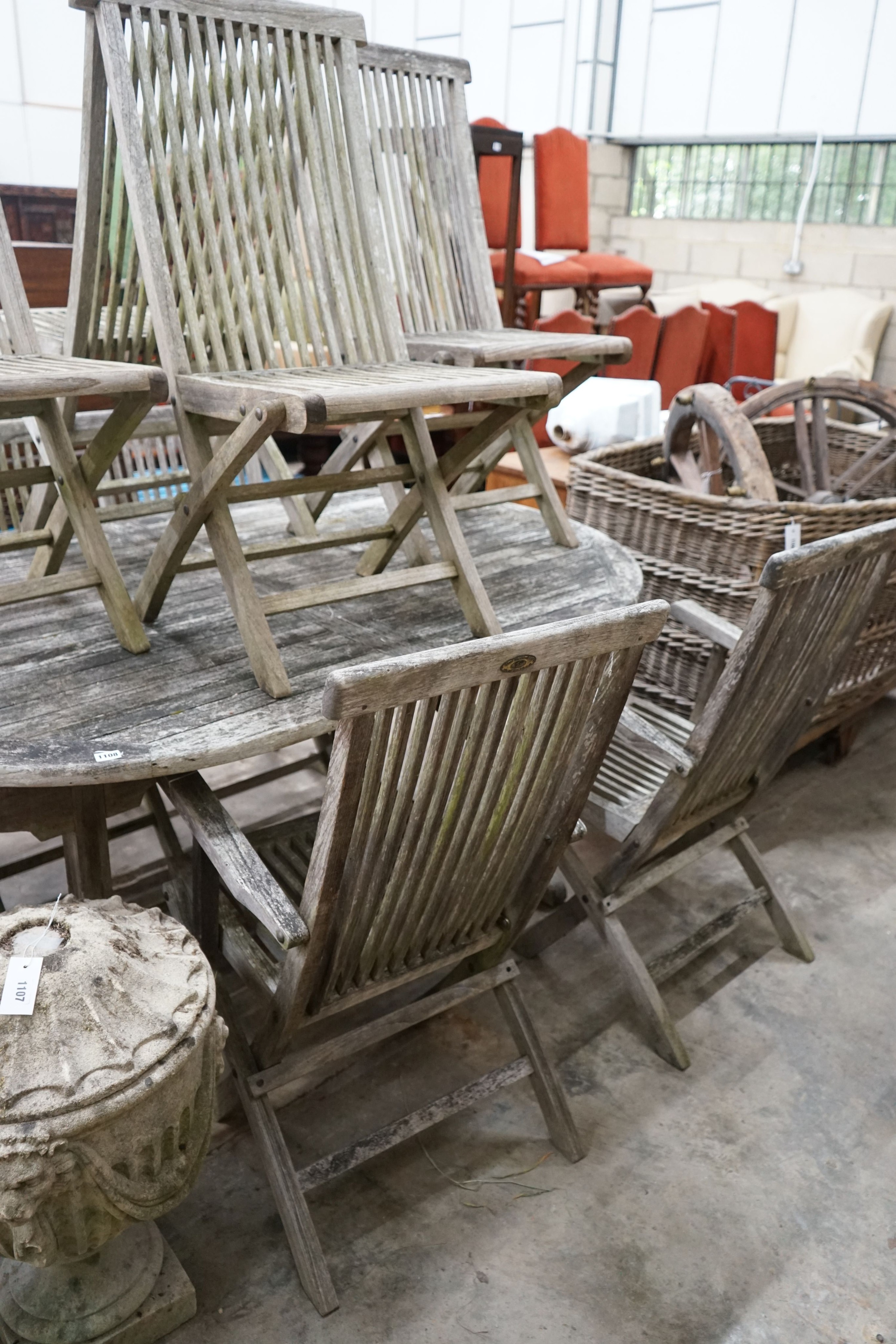 A weathered teak oval garden table, length 178cm, width 120cm, height 77cm and eight folding chairs, two with arms